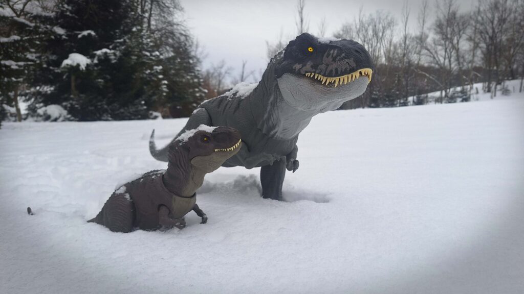 Toy photography dinosaur short story scene of a T-Rex dad and child in a snowy forest after a blizzard.