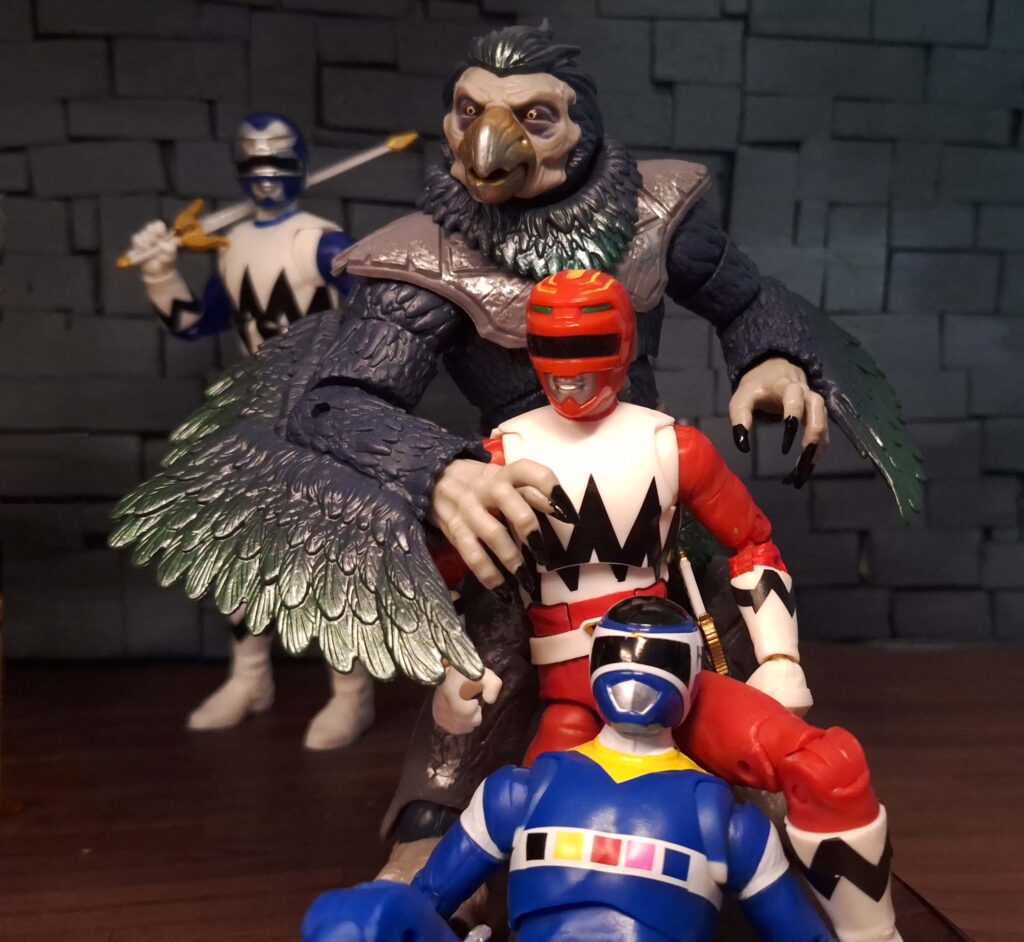 Tenga Warrior standing protectively near Blue Space Ranger while Red Galaxy Ranger helps him sit up inside The Nexus Dive bar